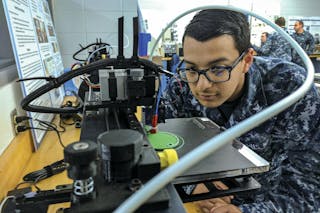 Navy Petty Officer 3rd Class Daniel Pastor examines a 3-D printer during a 3-D design and production course at Old Dominion University in Norfolk, Va., to service members how to design and print objects and parts that can help the fleet.