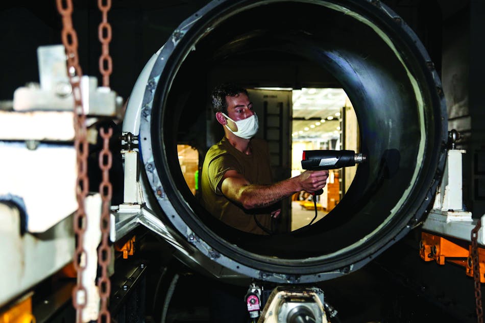An aviation machinist&rsquo;s mate aboard the aircraft carrier USS Abraham Lincoln performs a liquid crystal test to reveal possible delamination of an engine run trailer.