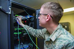 An Air Force cyber transport technician connects fiber optic cables to switches at the network control center on Holloman Air Force Base, N.M.