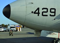 A U.S. Navy electronic warfare operator watches the exterior of a P-8A Poseidon maritime patrol aircraft during a high-frequency radio check before a mission.