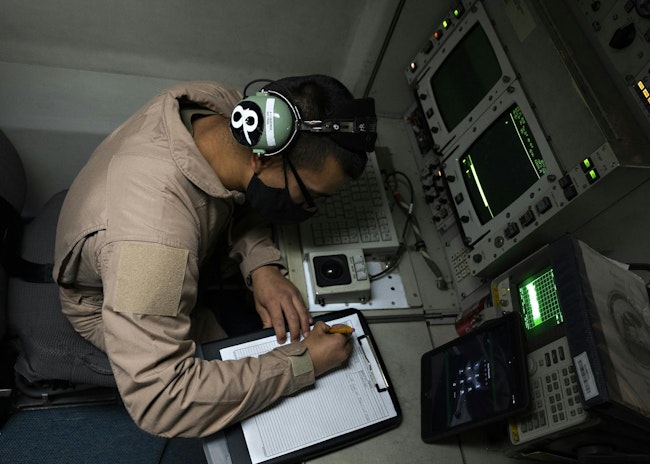 A U.S. Air Force senior airman writes down radar data while flying in an E-3 over Southwest Asia while flying a mission aboard the E-3 Sentry radar reconnaissance aircraft.