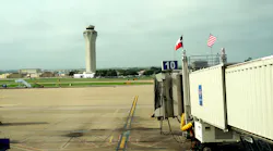 Texas and American flags fly above waiting jetway at Austin-Bergstrom airport. Air traffic control tower is in the background. Photo 56407993 © Linda Williams | Dreamstime.com