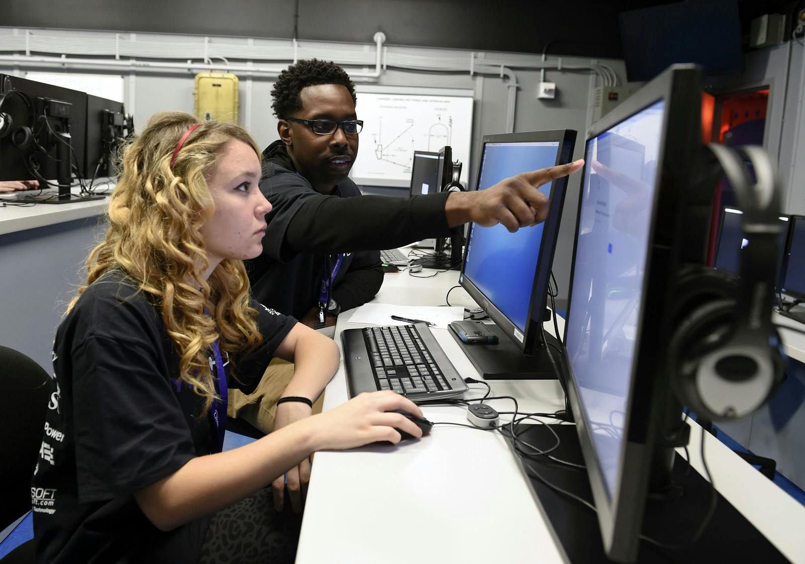 A U.S. military network cryptologic technician helps a high school student complete cyber security challenges. Navy photo