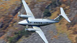 A King Air twin prop plane banks while in flight.