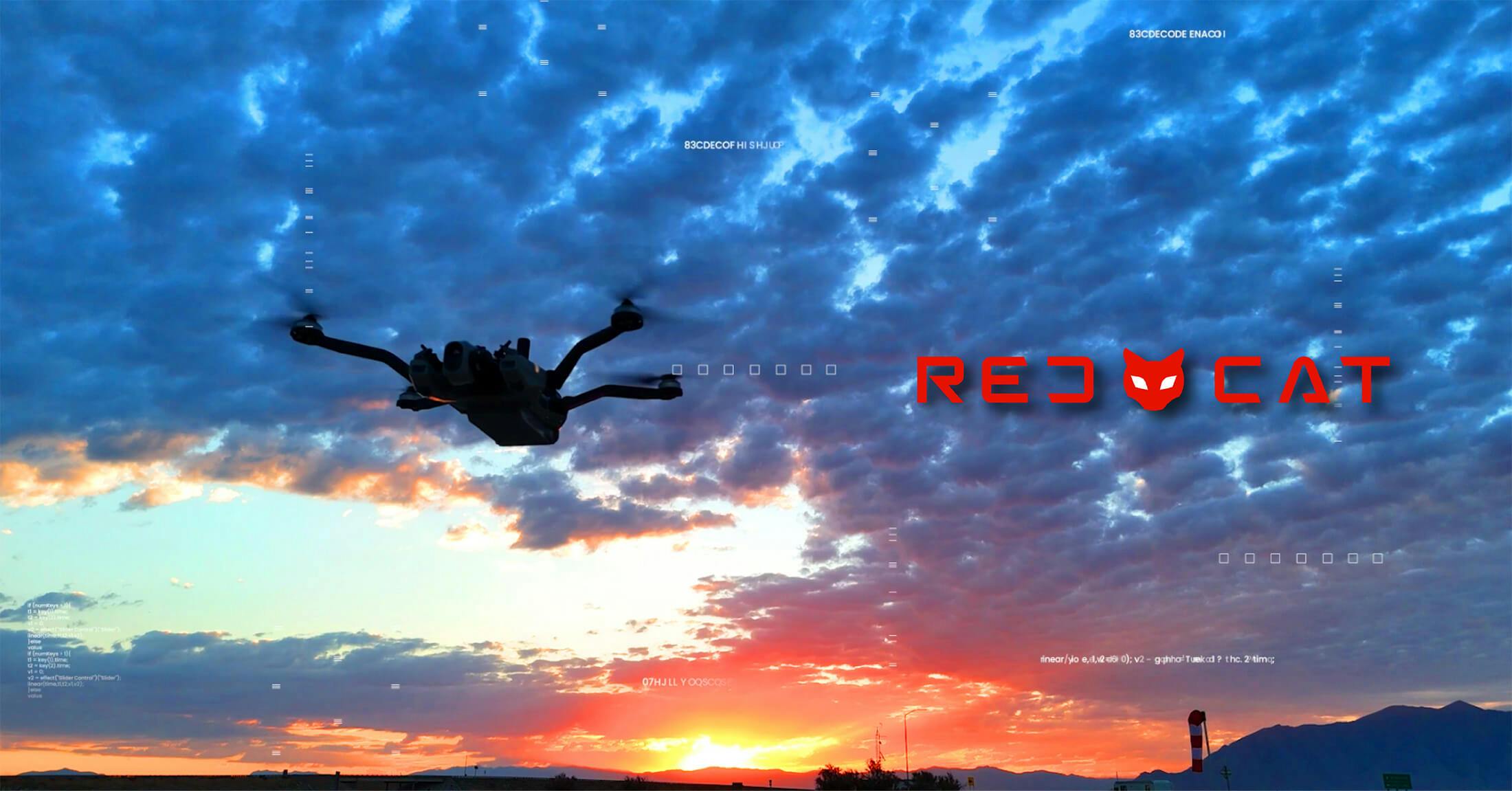 A quadcopter flies as the sun rises in the distance with the Red Cat logo off to the side.