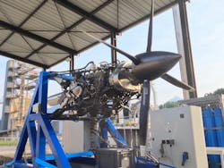 A photo of an unshrouded propeller aircraft engine on a stand. A photo of an unshrouded propeller aircraft engine on a stand.