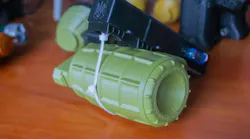 Small models of grenade defensive weapon printed on 3D printer from molten plastic on table.
