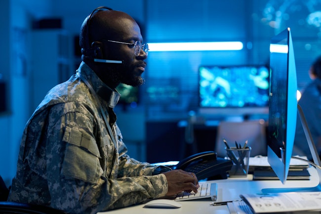 A military operator types on keypad and looks at computer screen.