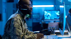 A military operator types on keypad and looks at computer screen.