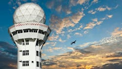 An air traffic control tower with a silhouetted airplane flying in the background An air traffic control tower with a silhouetted airplane flying in the background