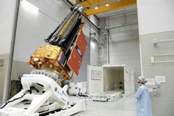 A person in a clean room watches the Biomass satellite prepared to be loaded into a container A person in a clean room watches the Biomass satellite prepared to be loaded into a container