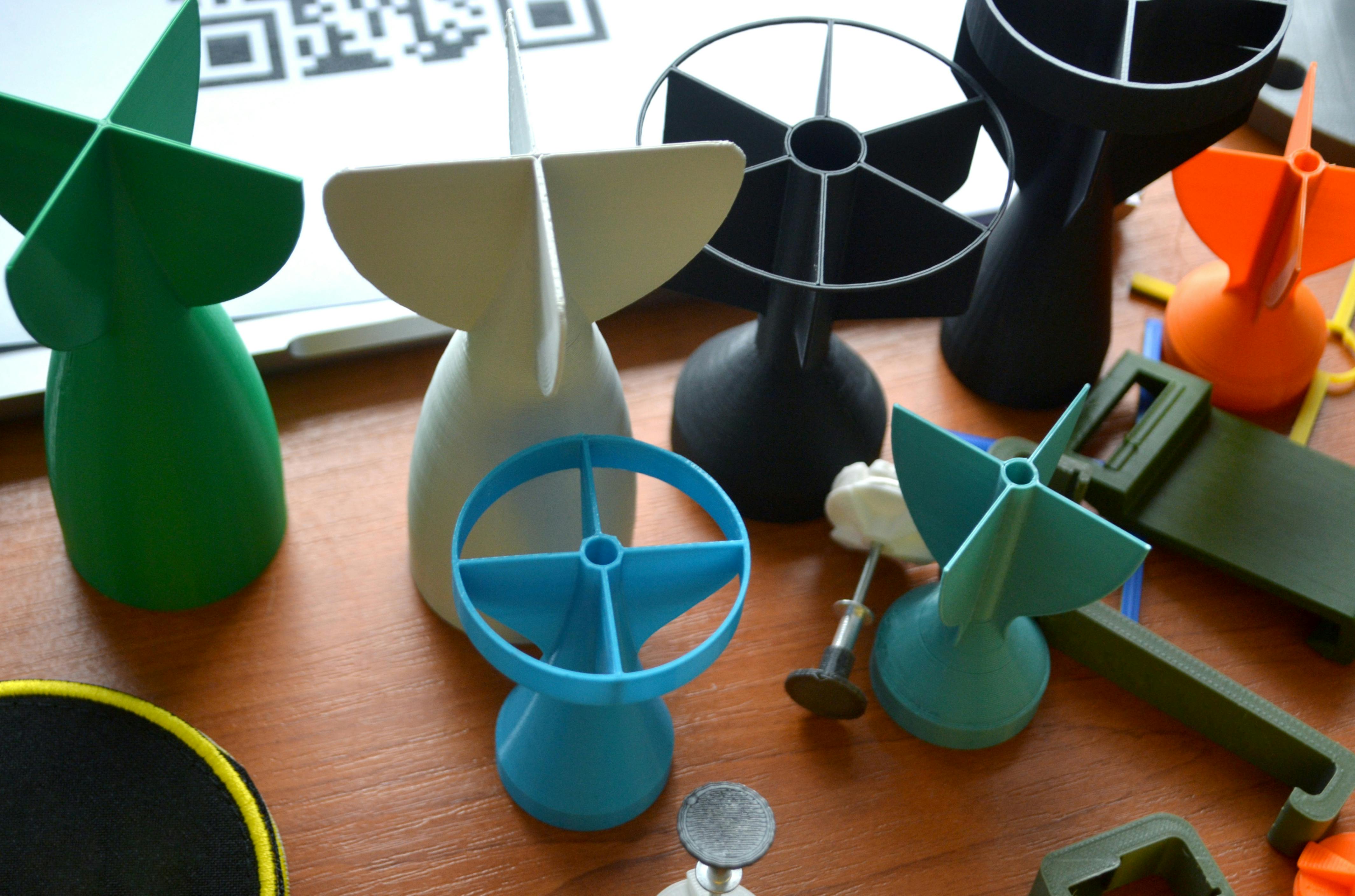 Prototype model of rocket bomb tip, colored models of tail fins, and tail cone printed on a 3D printer from molten plastic.