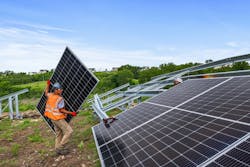 A worker carries a solar panel to an array A worker carries a solar panel to an array