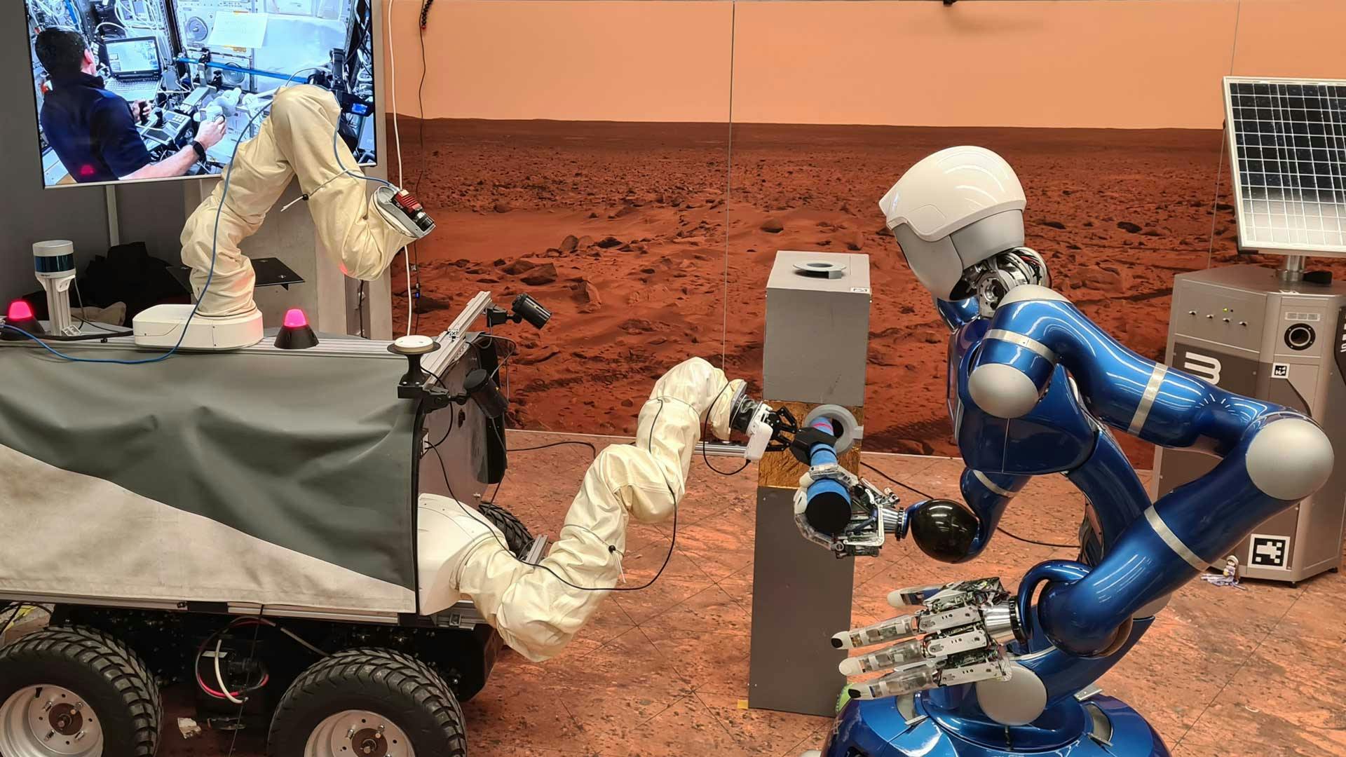 DLR's autonomous humanoid robot Rollin' Justin (right) and the ESA Interact Rover (left) being controlled from the International Space Station ISS. They are cooperating on the handling of a tool. Credit: DLR (CC BY-NC-ND 3.0).