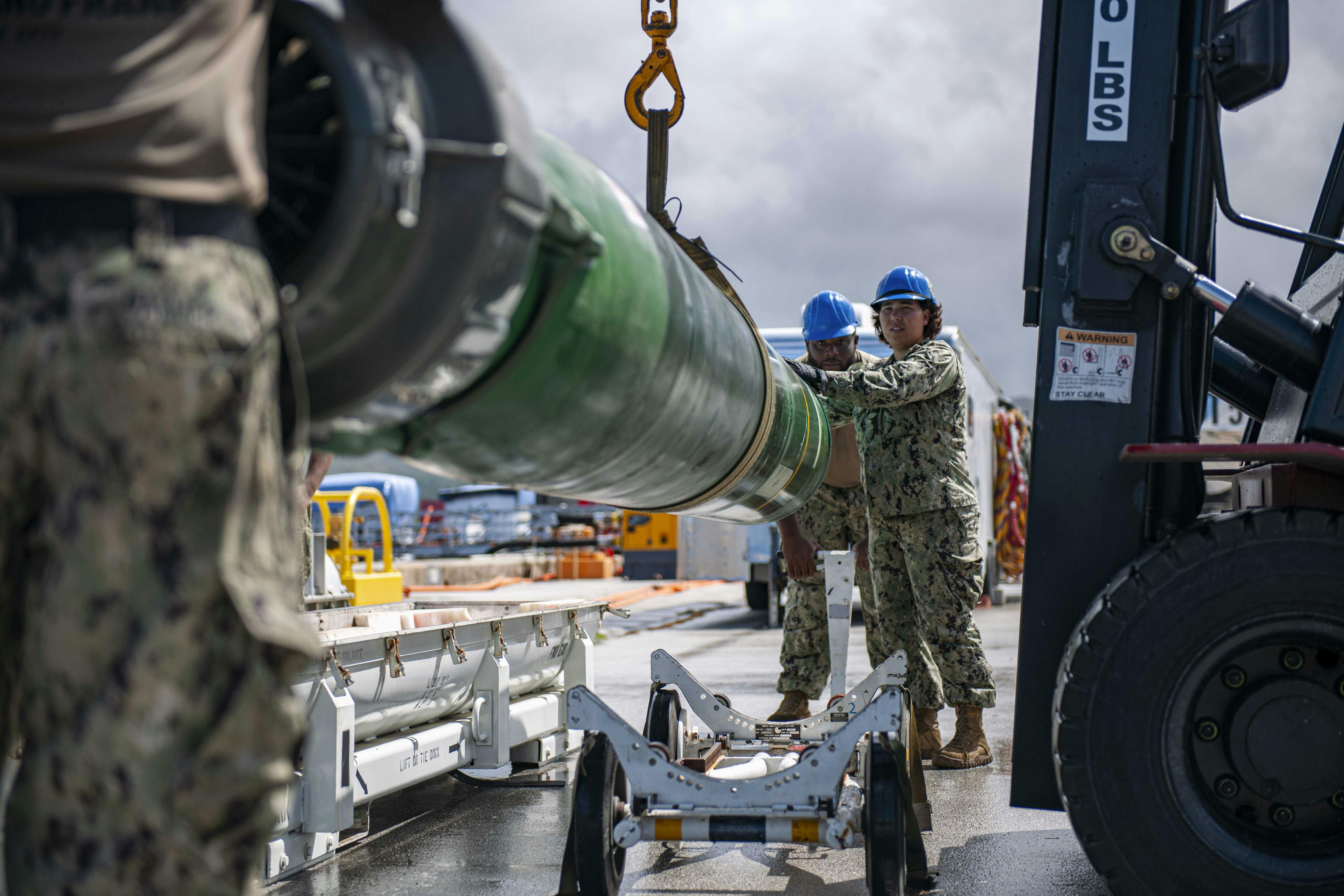 Sailors from a U.S. submarine tender guide a MK 48 torpedo during a weapons load of the Los Angeles-class fast-attack submarine USS Annapolis (SSN 760) at U.S. Naval Base Guam.