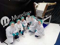 A group of people in cleanroom clothing pose in front of a satellite A group of people in cleanroom clothing pose in front of a satellite