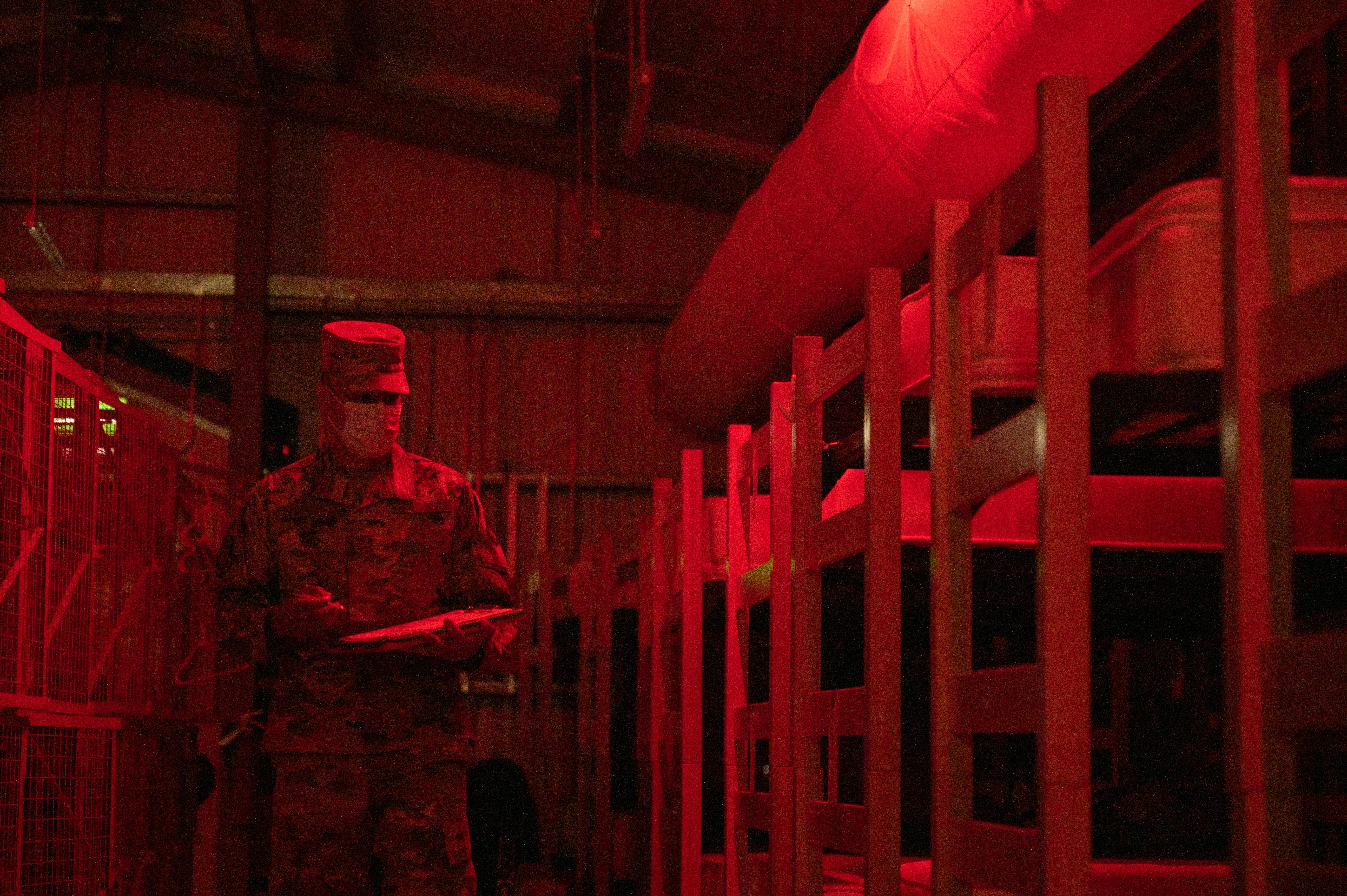 An Air Force lodging specialist performs accountability checks throughout the transient tents on Ali Al Salem Air Base, Kuwait. The red light does not disturb sleeping airmen during tent checks.