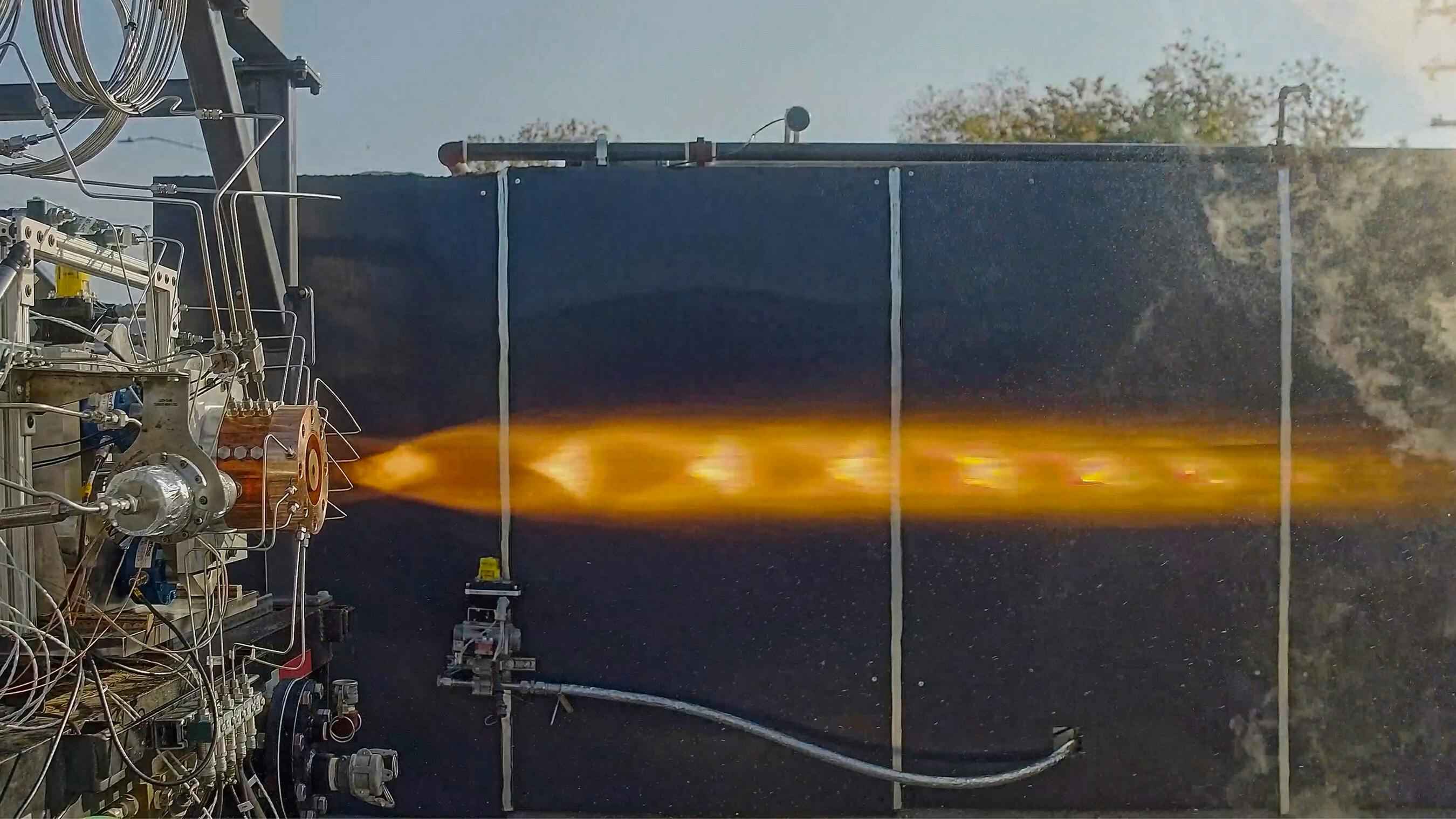 An imagine in profile of a rocket engine emitting a large flame horizontally