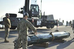 A U.S. Navy equipment operator signals the crane to lower the hook to attach an MK 48 inert training torpedo during an expeditionary ordnance loading exercise. A U.S. Navy equipment operator signals the crane to lower the hook to attach an MK 48 inert training torpedo during an expeditionary ordnance loading exercise.