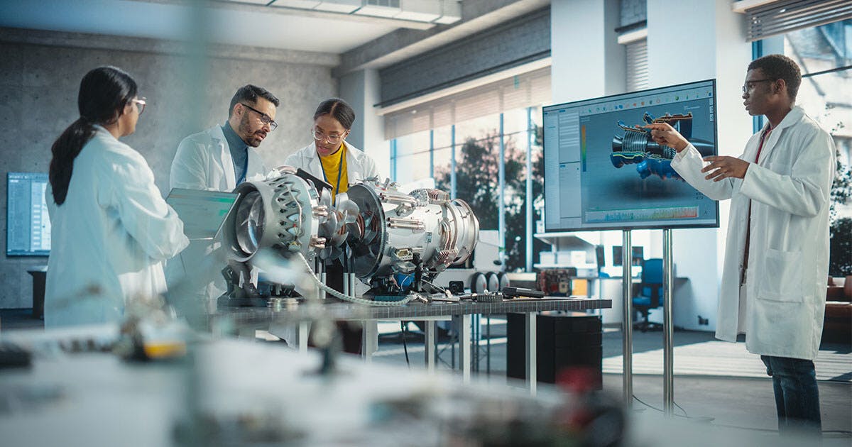 Four researchers in lab coats work on an aircraft engine