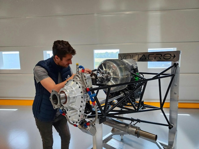 A technician looks at the hybrid engine as it sits on a stand