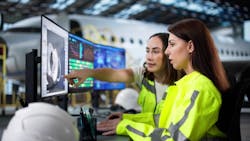 Two women look at a computer screen in an airplane hangar Two women look at a computer screen in an airplane hangar