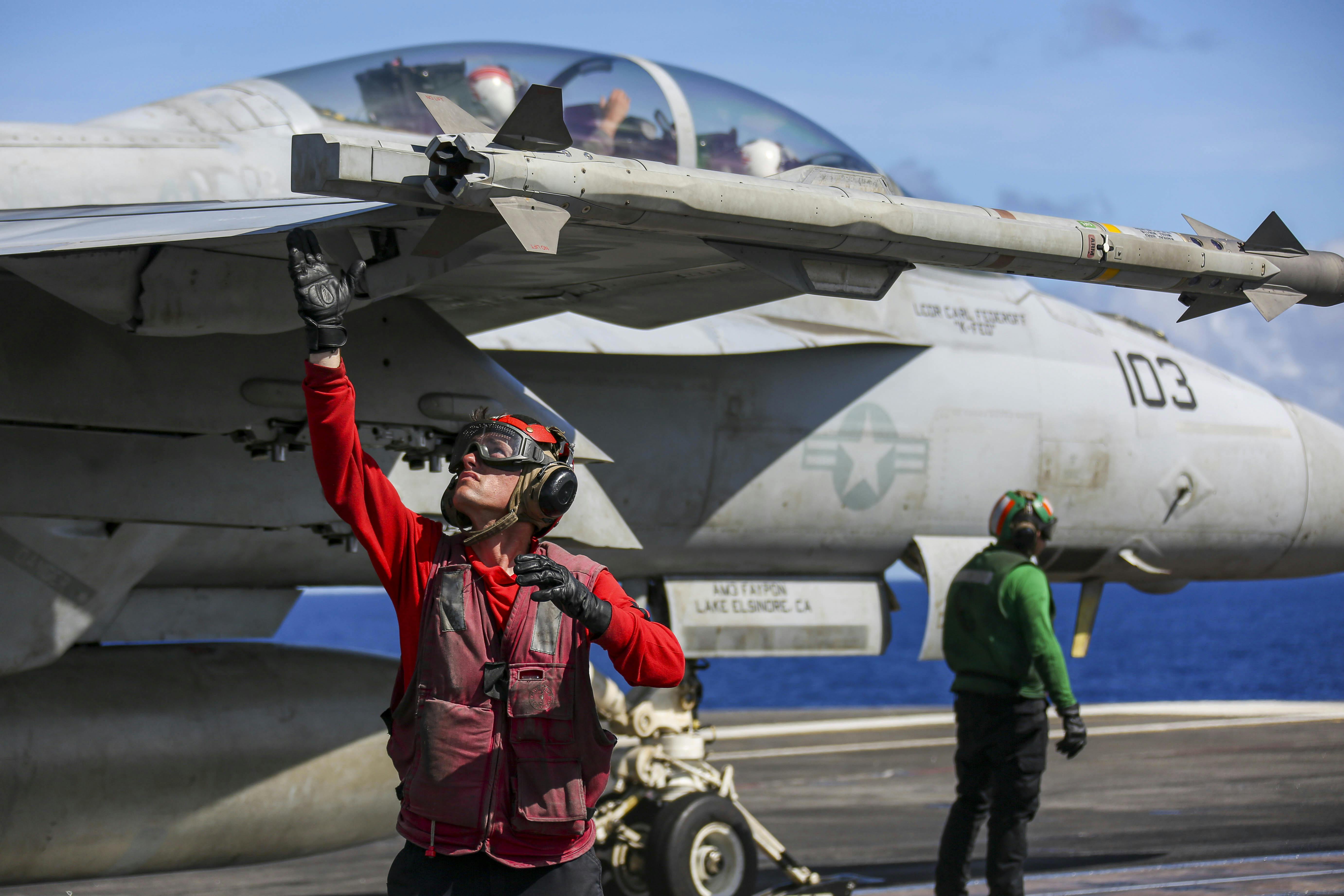 A Navy aviation ordnanceman arms up an AIM-9X missile on an F/A-18F Super Hornet on the flight deck of the Nimitz-class aircraft carrier USS Abraham Lincoln (CVN 72)