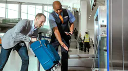 A JetBlue employee directs a passenger to place their bag on a stand.