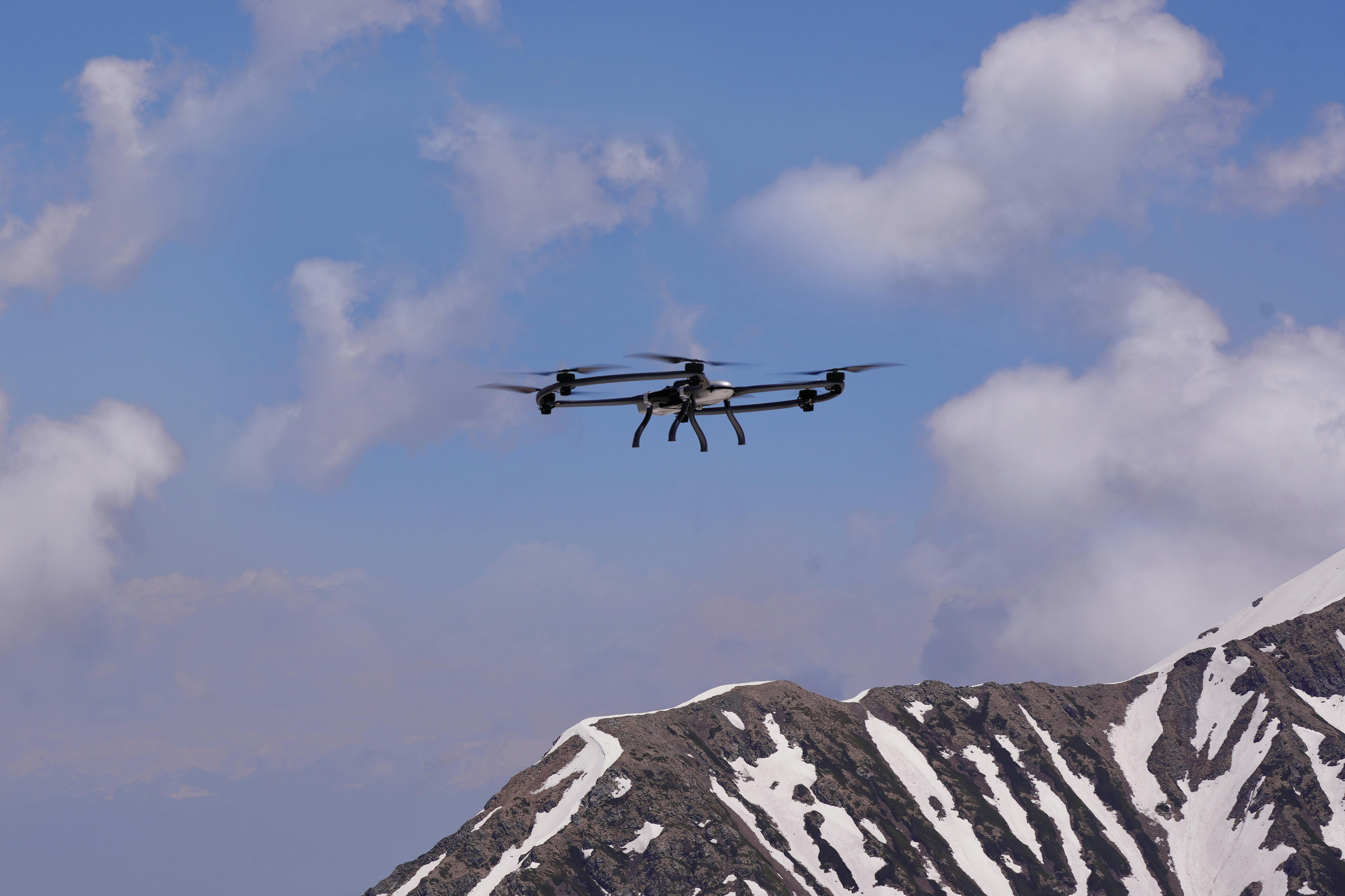 A small quadcopter drone flying with a mountain in the background