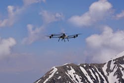 A small quadcopter drone flying with a mountain in the background A small quadcopter drone flying with a mountain in the background