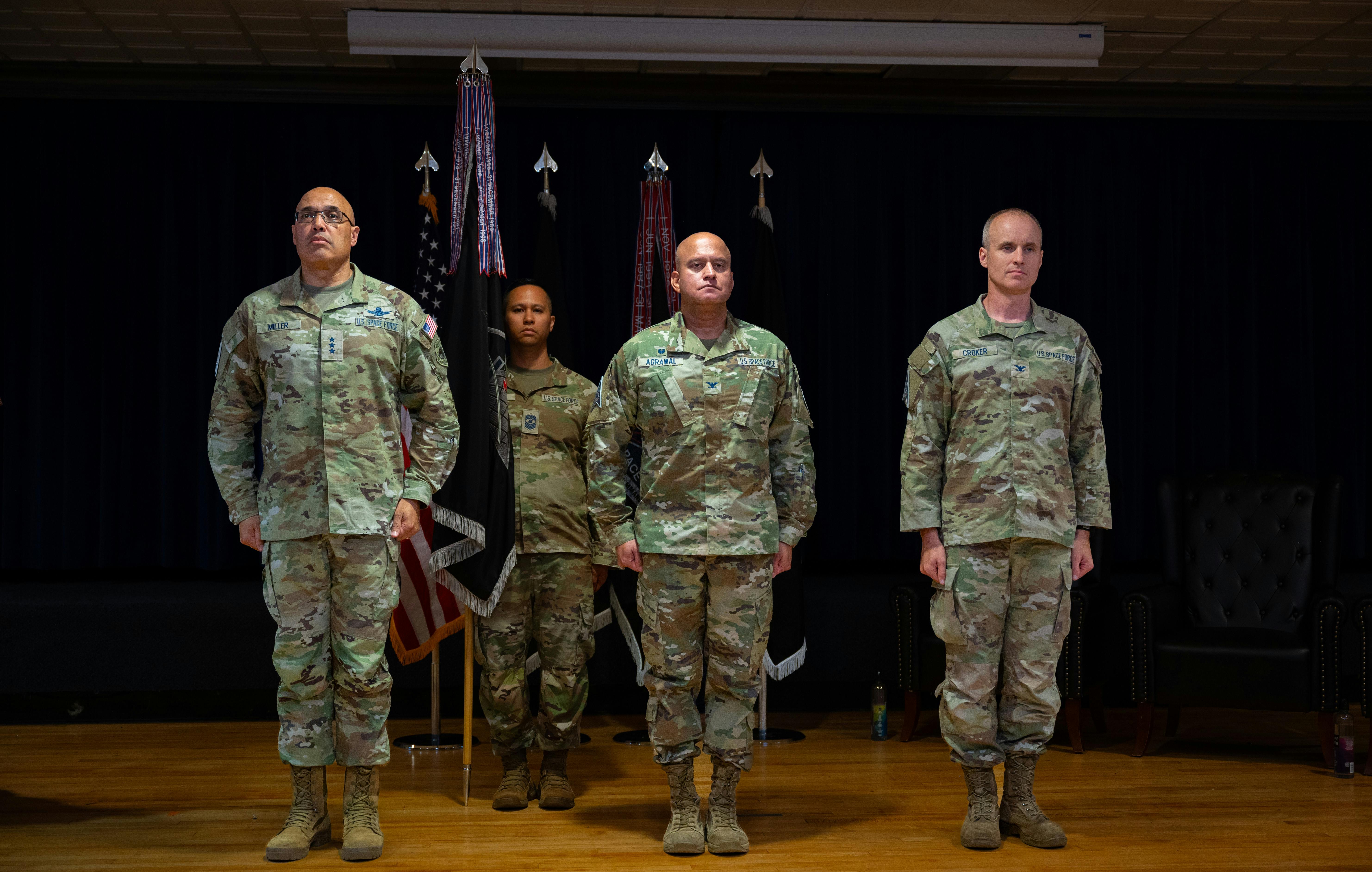 U.S. Space Force Lt. Gen. David N. Miller, Jr., commander of Space Operations Command, U.S. Space Force Col. Raj Agrawal, and U.S. Space Force Barry Coker stand at attention as Col. Agrawal prepares to relinquish command of Mission Delta 2 to Col. Croker during a change-of-command ceremony, July 3, 2025, at Peterson SFB, Colo. U.S. Space Force photo.