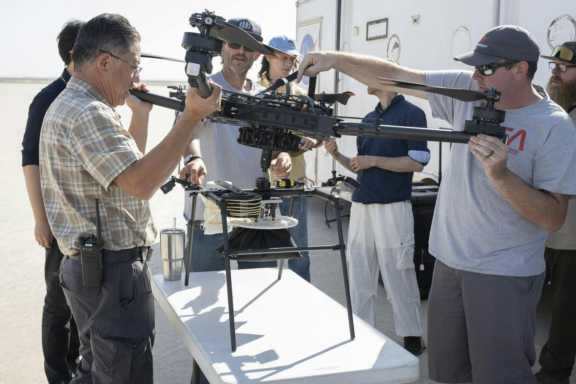 Derek Abramson, left, and Justin Link, right, attach an Alta X drone to the Enhancing Parachutes by Instrumenting the Canopy test experiment on June 4, 2025, at NASA&rsquo;s Armstong Flight Research Center in Edwards, California. Abramson is NASA chief engineer at the center&rsquo;s Dale Reed Subscale Flight Research Laboratory, where Link also works as a pilot for small uncrewed aircraft systems. NASA researchers are developing technology to make supersonic parachutes safer and more reliable for delivering science instruments and payloads to Mars. NASA/Christopher LC Clark image.