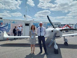 A photo of a man and a woman standing next to an uncrewed aircraft on the tarmac. A photo of a man and a woman standing next to an uncrewed aircraft on the tarmac.