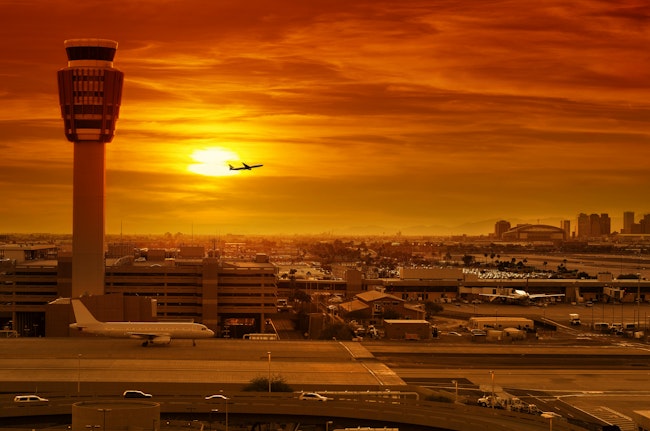 An ATC tower at an airport in front of a sunrise or sunset.