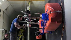 Technicians install and adjust the rotors on the full-scale test model representing half of the Dragonfly lander in the Transonic Dynamics Tunnel facility at NASA’s Langley Research Center. During a month-long testing campaign, the team was able to evaluate rotor system performance in Titan-like conditions. NASA photo. Technicians install and adjust the rotors on the full-scale test model representing half of the Dragonfly lander in the Transonic Dynamics Tunnel facility at NASA’s Langley Research Center. During a month-long testing campaign, the team was able to evaluate rotor system performance in Titan-like conditions. NASA photo.