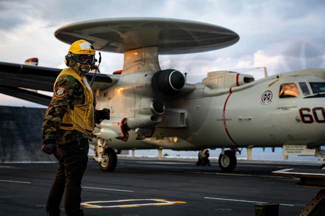 A Navy aviation boatswain’s mate signals to an E-2D Hawkeye radar surveillance aircraft earlier this month aboard the aircraft carrier USS Gerald R. Ford.