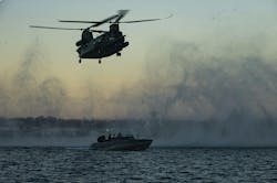 A U.S. MH-47 Chinook heavy assault helicopter lowers a hoist cable to a combatant craft during a maritime training evolution. A U.S. MH-47 Chinook heavy assault helicopter lowers a hoist cable to a combatant craft during a maritime training evolution.