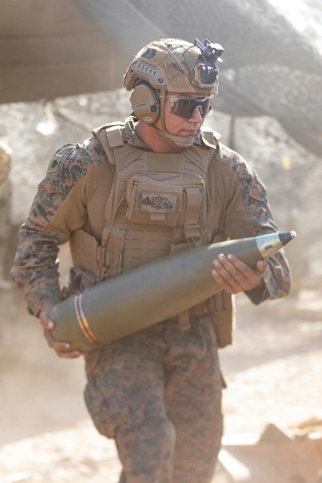 A U.S. Marine Corps howitzer section chief loads a high-explosive projectile into an M777A2 medium towed 155-millimeter howitzer during a 2024 field exercise.