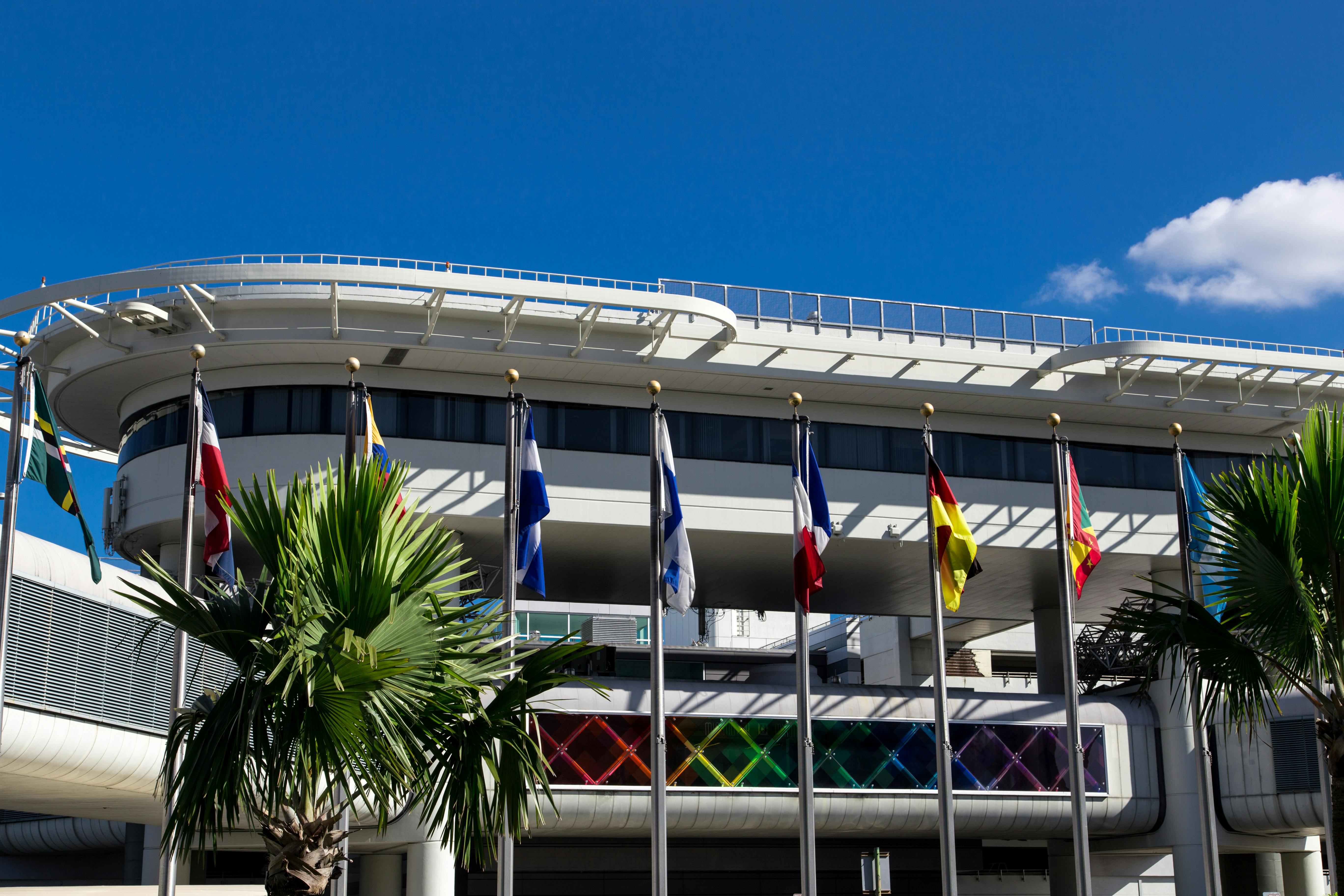 An exterior photo of MIA with international flags on poles outside.
