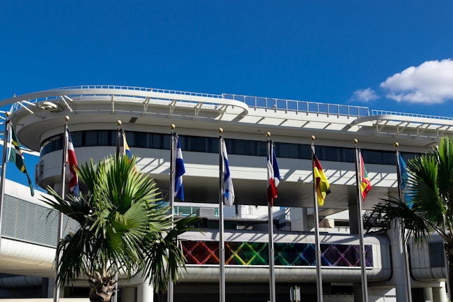 An exterior photo of MIA with international flags on poles outside.