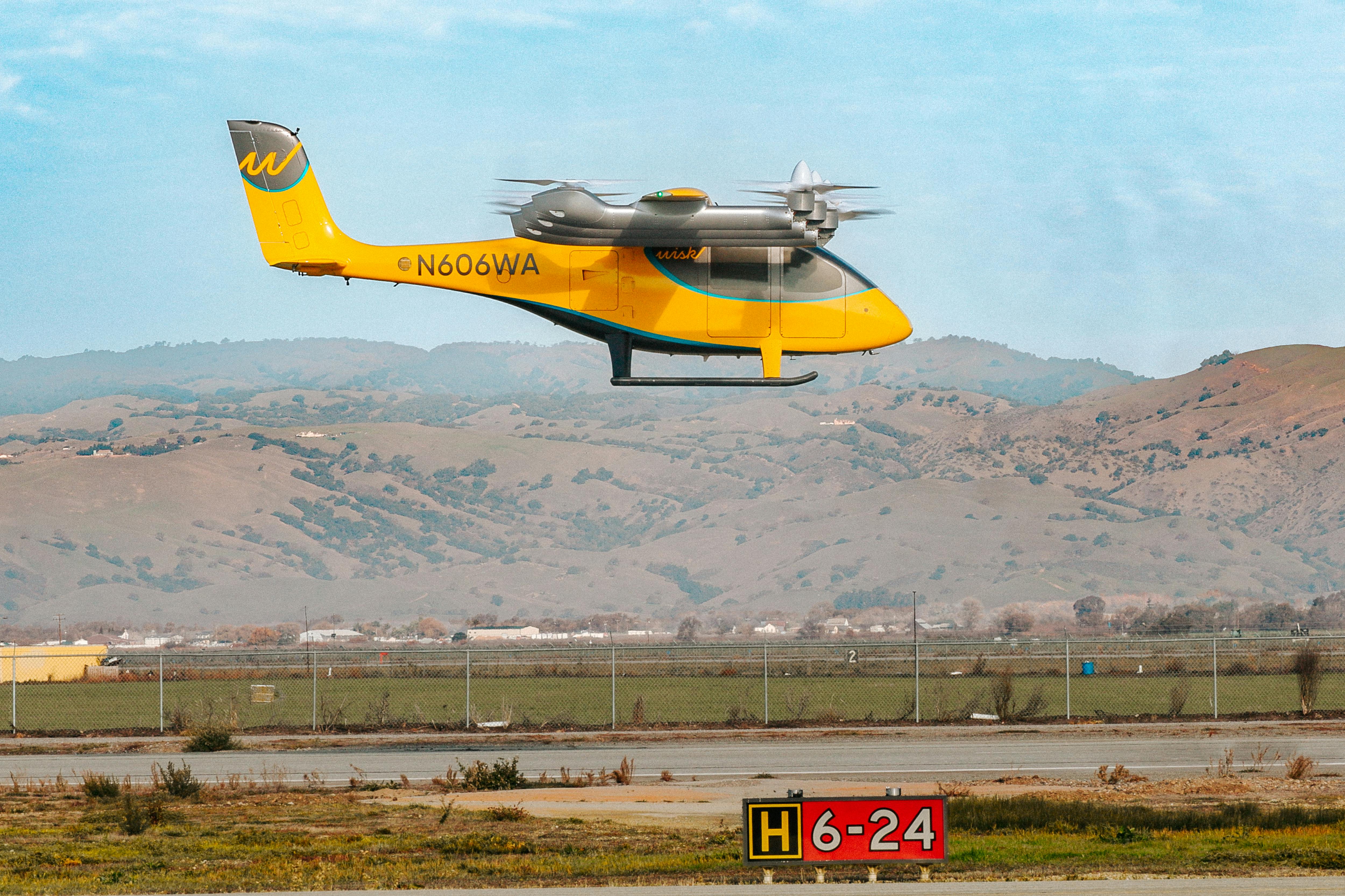 Wisk's eVTOL hovers above the tarmac at its California test facility.