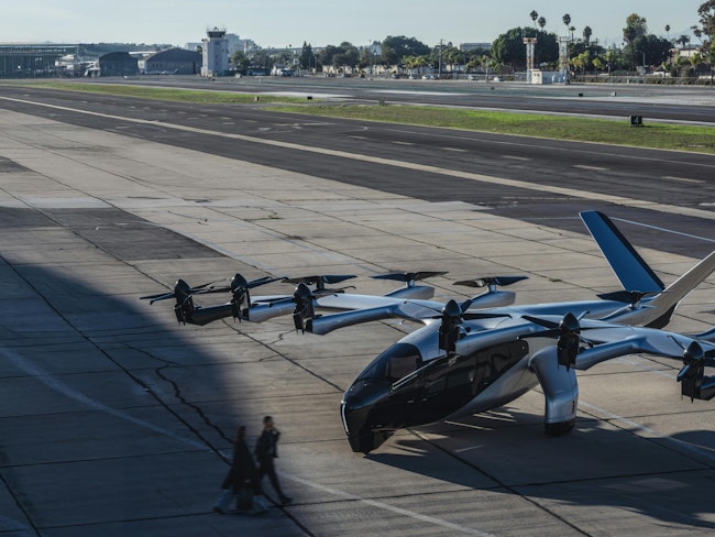 Two people approach an Archer eVTOL on the tarmac.