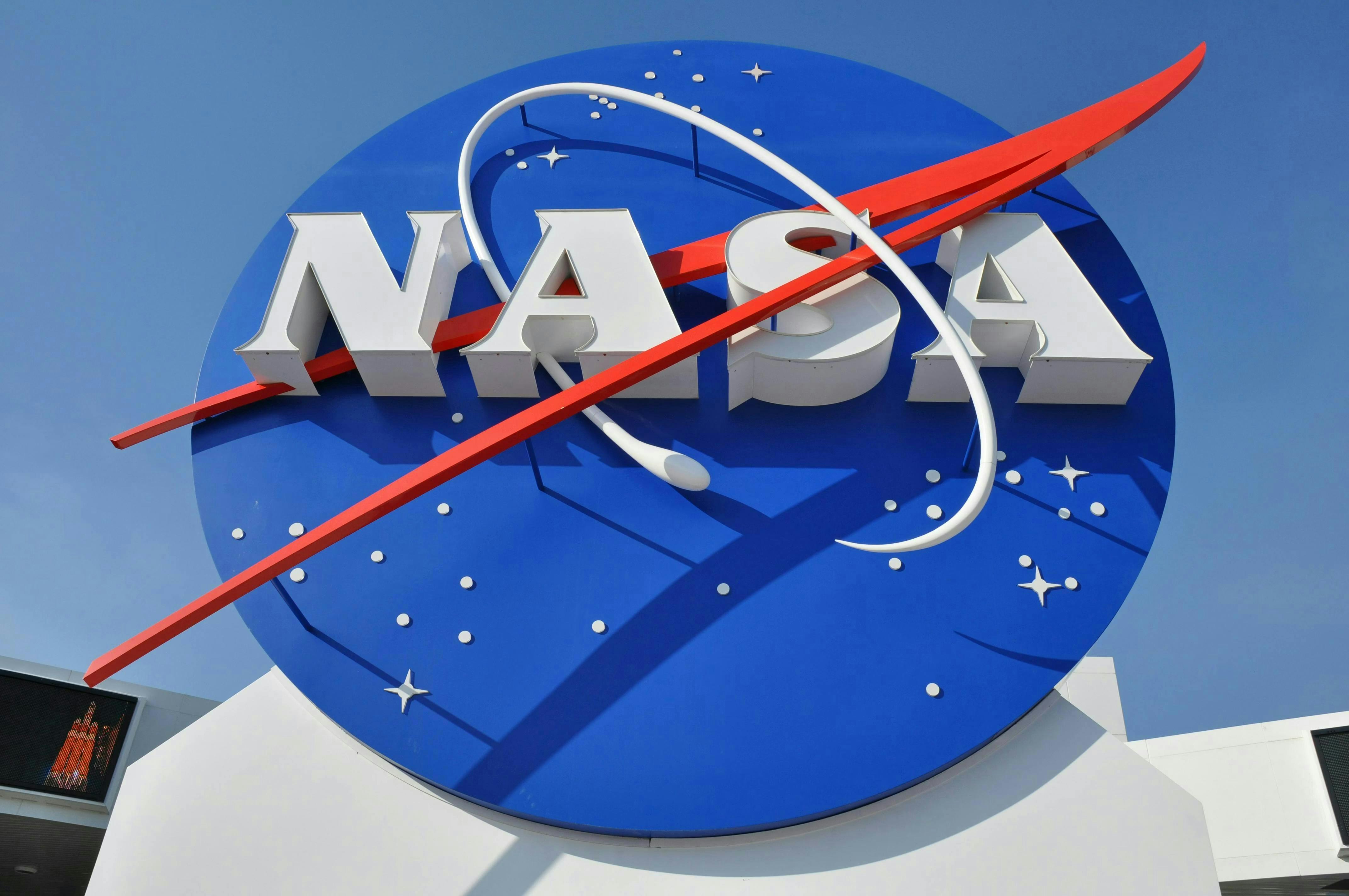 A sign bearing NASA's logo shot from a low angle beneath a blue sky.