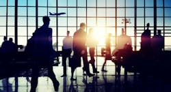 People in an airport terminal shown mostly in shadow. People in an airport terminal shown mostly in shadow.