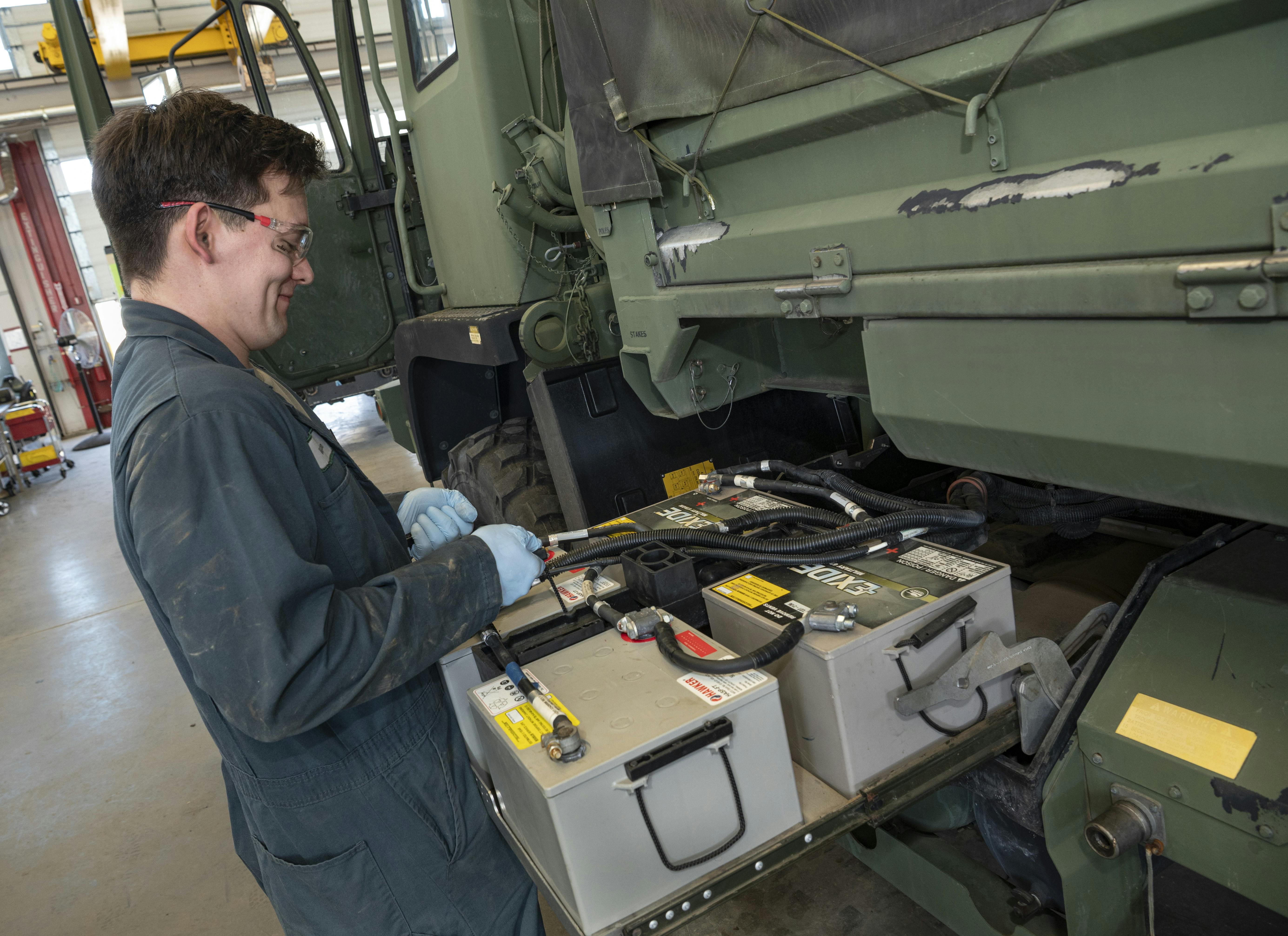 An Oregon Army National Guard soldier performs routine maintenance with the batteries on one of the many vehicles being repaired at the Combined Support Maintenance Shop at Camp Withycombe in Happy Valley, Ore., in March 2025.