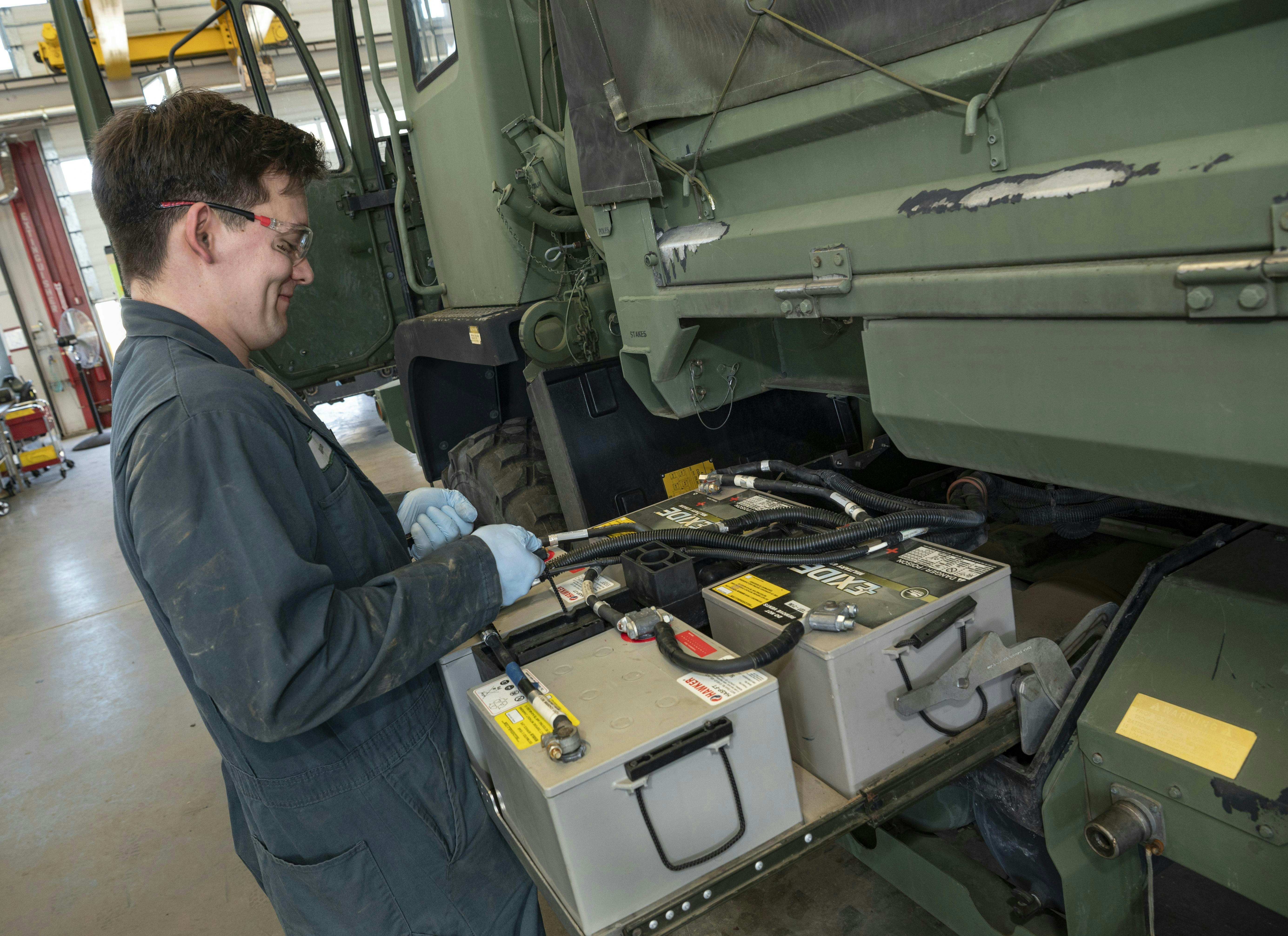 An Oregon Army National Guard soldier performs routine maintenance with the batteries on one of the many vehicles being repaired at the Combined Support Maintenance Shop at Camp Withycombe in Happy Valley, Ore., in March 2025.