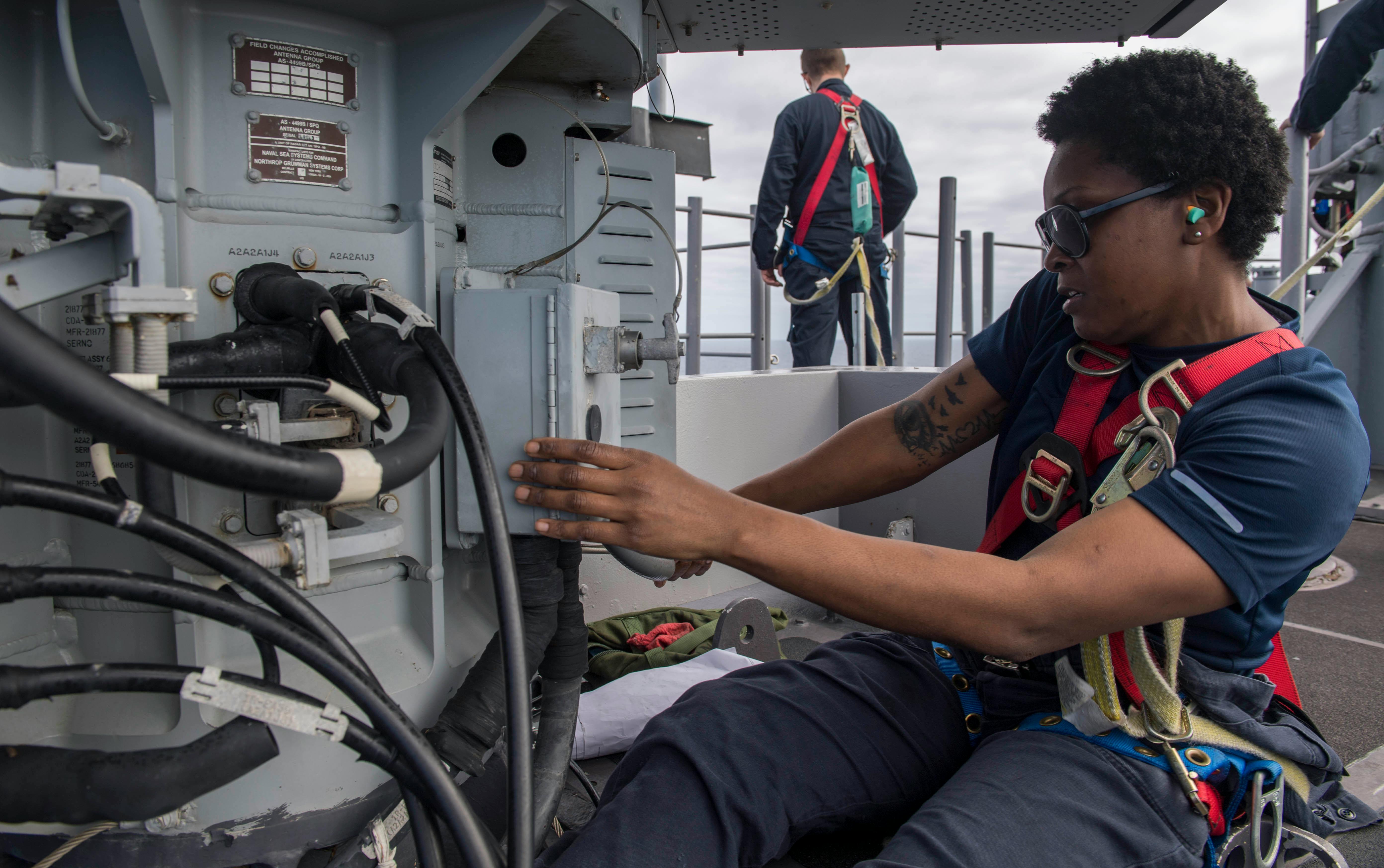 A Navy fire controlman lubricates the antenna pedestal on an AN/SPQ-9B fire control radar aboard the amphibious assault ship USS Iwo Jima (LHD 7).