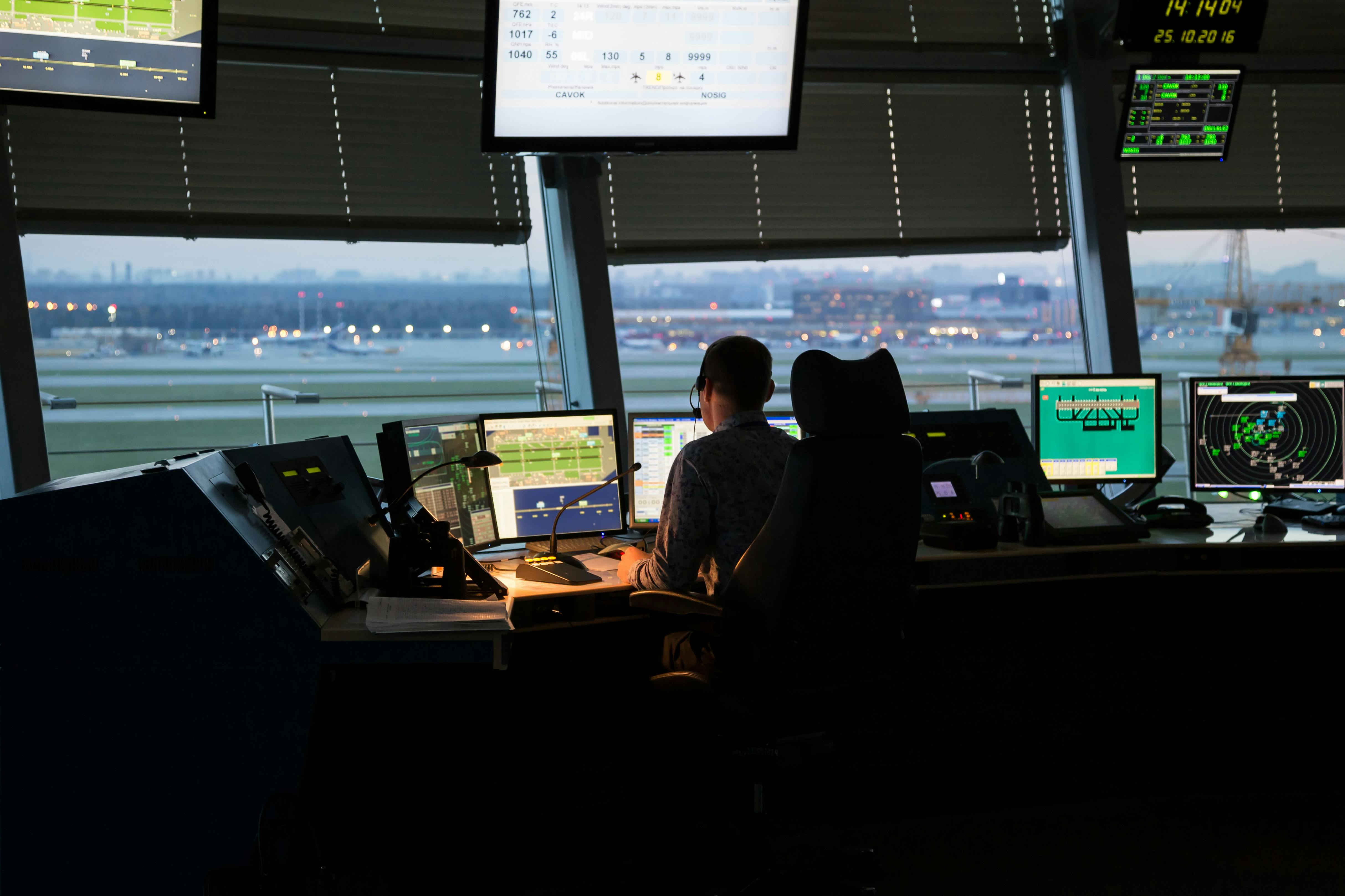 An air traffic controller working at an ATC console overlooking airport tarmac.