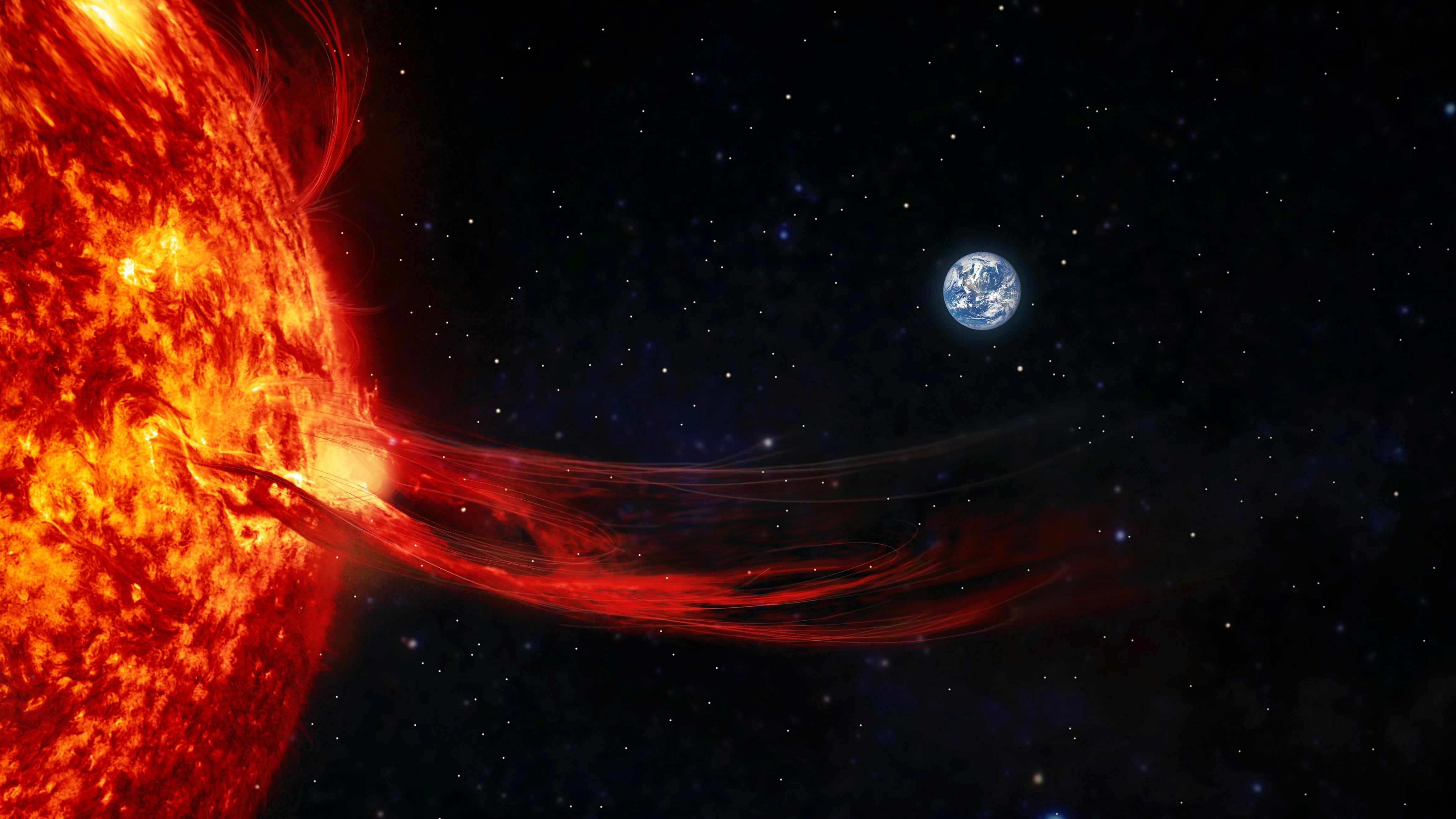 A flare emits from the sun with Earth visible in the background.