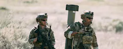 Two soldiers in field BDUs walk. One carries a rifle, the other, the Switchblade 400. Two soldiers in field BDUs walk. One carries a rifle, the other, the Switchblade 400.